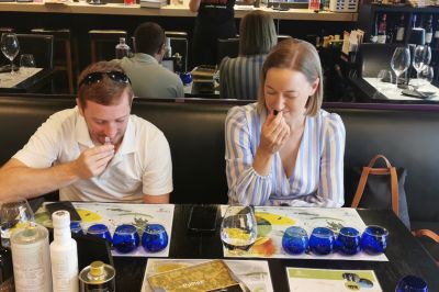 Couple tasting Greek extra virgin olive oil during a guided olive oil tasting in Athens.