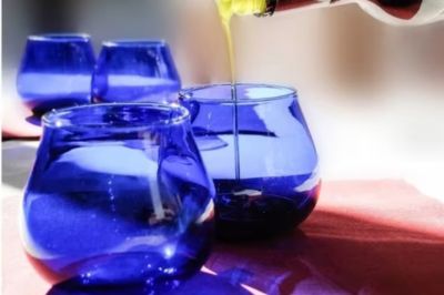 Greek extra virgin olive oil being poured into blue tasting glasses for an olive oil tasting in Athens.