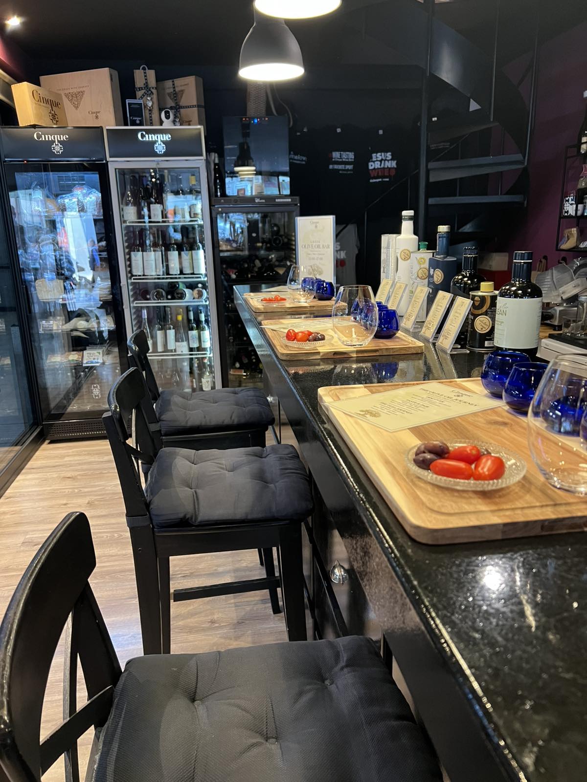 Discover the Greek Olive Oil Bar at Cinque Monastiraki Wooden olive oil tasting trays with blue glasses, cherry tomatoes and olives at the Cinque bar in Monastiraki.